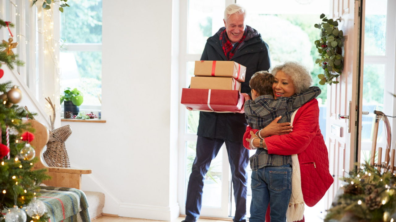 Excited grandson greeting grandparents with presents, gifts visiting On Christmas day