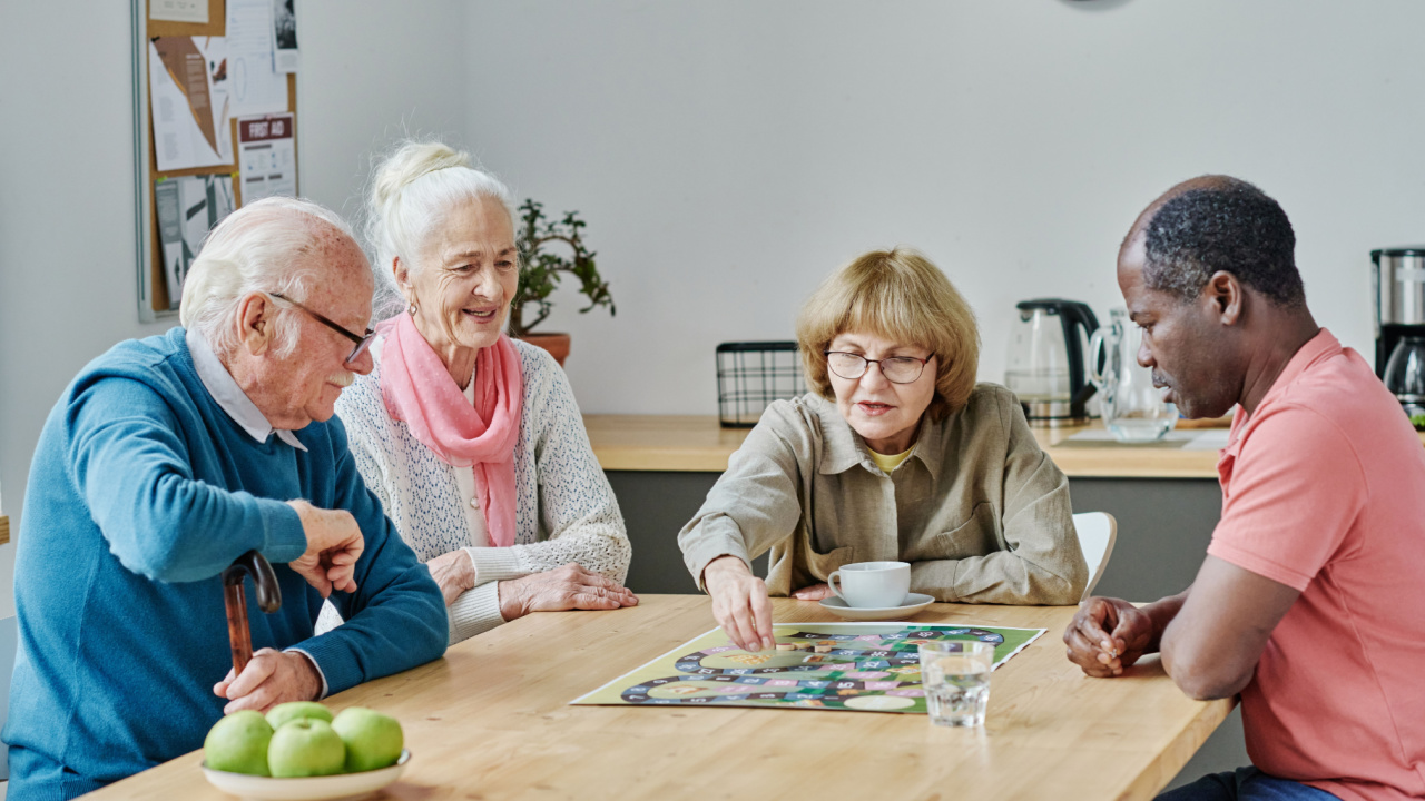 Four elderly friends playing drought and happy