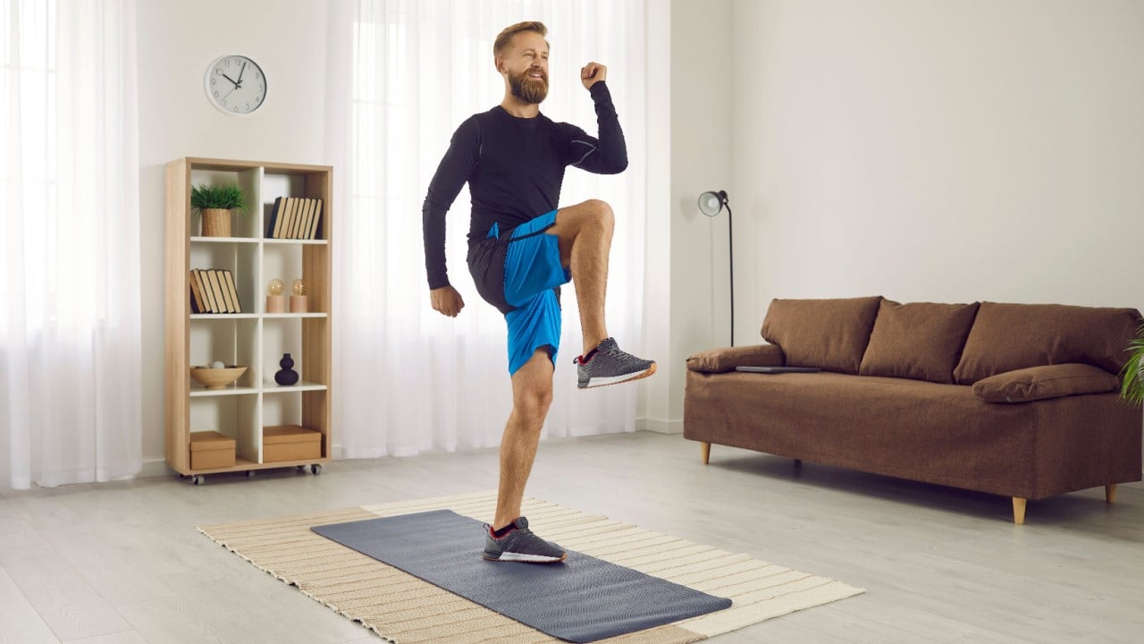 Male athlete fitness workout at home, doing high knees walk in place exercise and standing marches