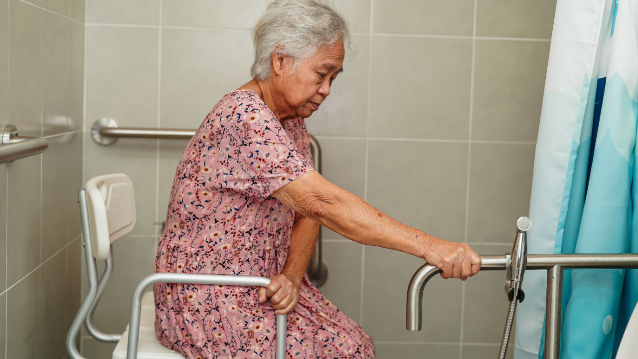 Senior or elderly old lady woman use toilet bathroom handle, holding grab bars