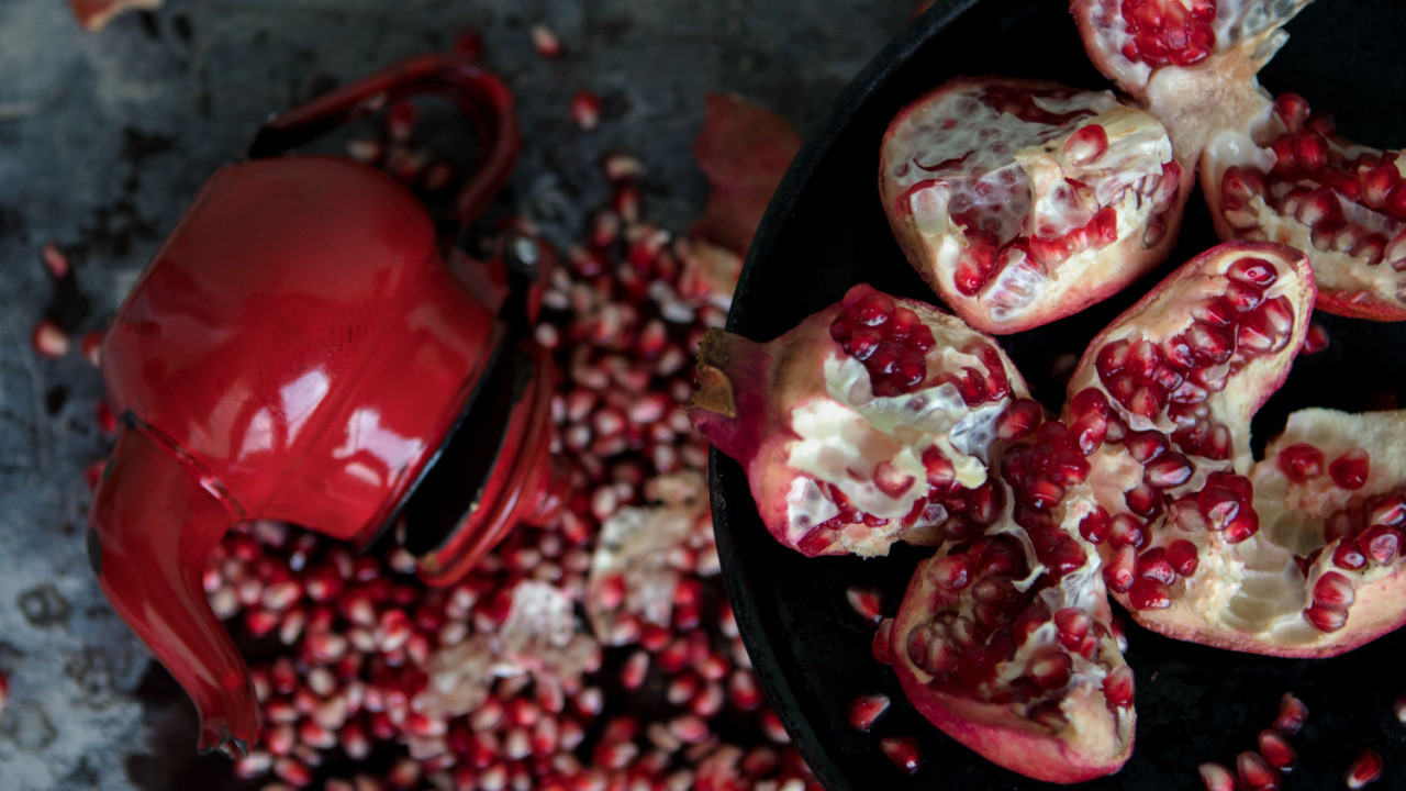 Smashed, cut out pomegranates on a black tray