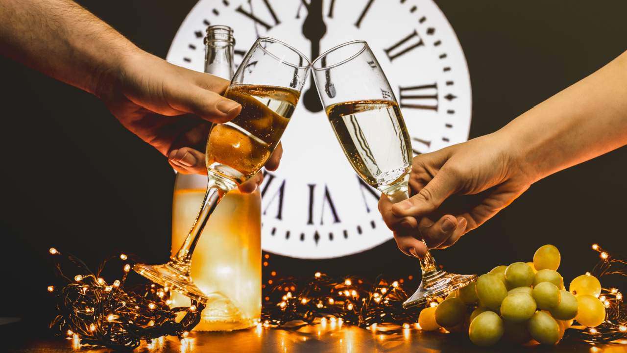 Toast to the new year with two glasses of champagne, New Year's Eve 12 grapes of luck eaten with the last 12 chimes of the year