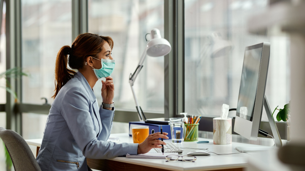 Young businesswoman wearing face mask while working on a computer in the office, avoid flu pandemic